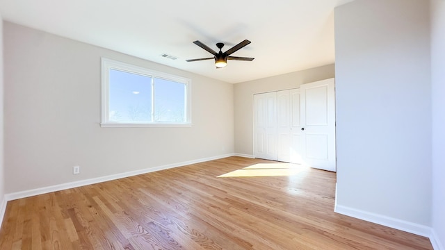 unfurnished bedroom featuring light wood-type flooring, visible vents, a closet, baseboards, and ceiling fan