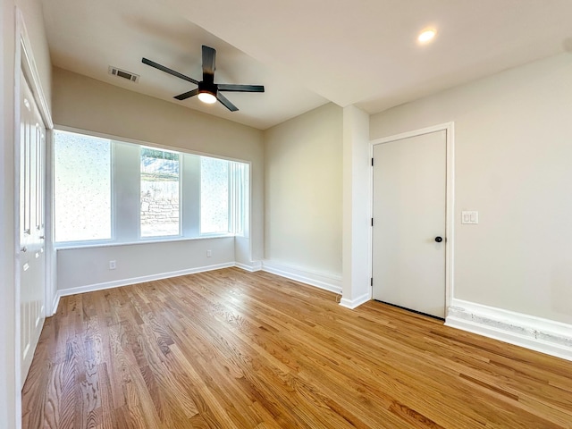 spare room with visible vents, baseboards, wood finished floors, and a ceiling fan