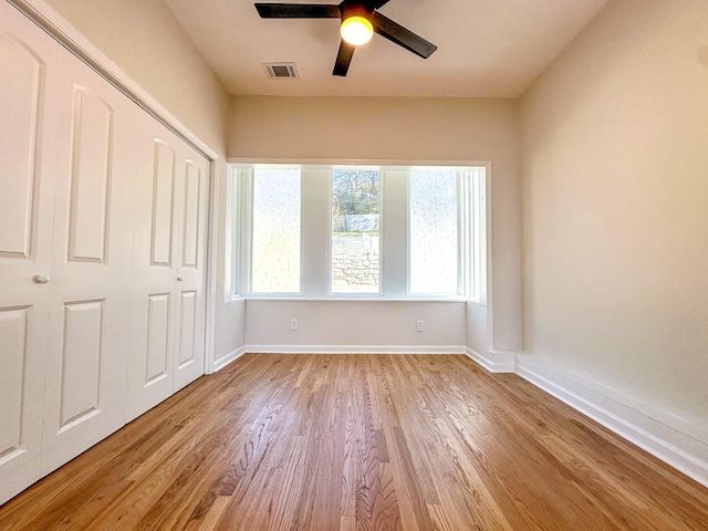 unfurnished bedroom featuring light wood-style flooring, visible vents, baseboards, and a closet