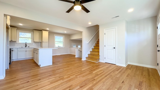 kitchen with visible vents, backsplash, ceiling fan, light countertops, and light wood-style floors