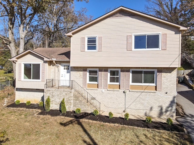 tri-level home featuring brick siding and a front yard