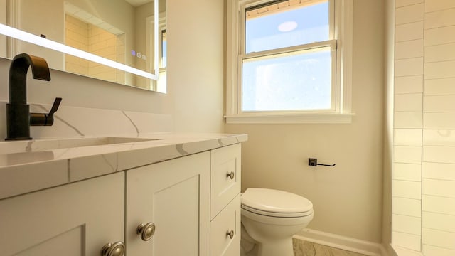 bathroom featuring toilet, vanity, and baseboards