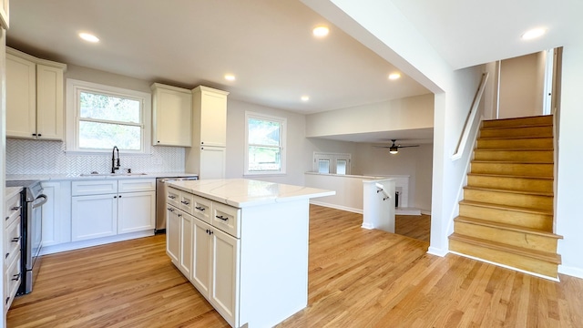 kitchen with a sink, plenty of natural light, tasteful backsplash, appliances with stainless steel finishes, and light wood finished floors