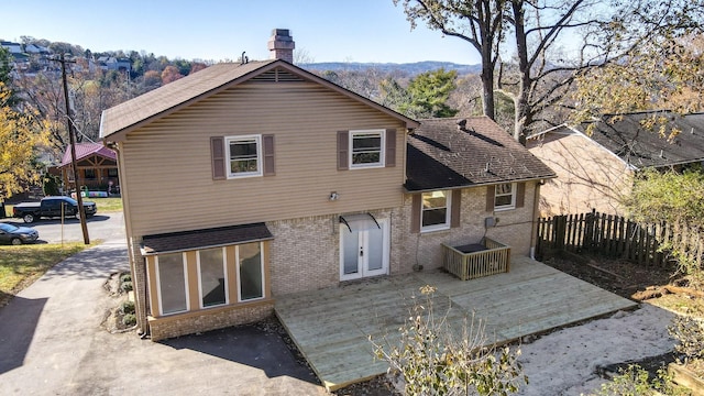 rear view of property featuring brick siding, a patio area, a chimney, and fence