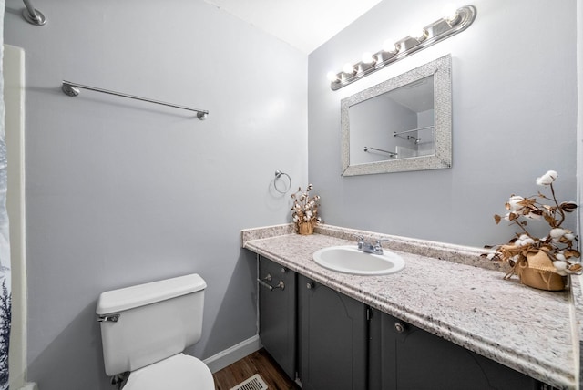 bathroom featuring baseboards, toilet, a shower with shower curtain, wood finished floors, and vanity