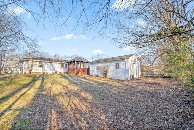 rear view of property featuring stucco siding, an outbuilding, and a lawn