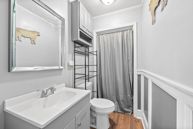 bathroom featuring a wainscoted wall, toilet, ornamental molding, wood finished floors, and vanity