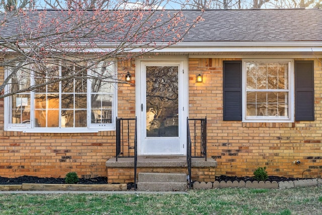 property entrance with brick siding and a shingled roof