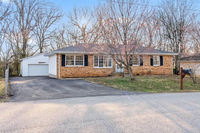 ranch-style house featuring an outbuilding, brick siding, a garage, and a front yard