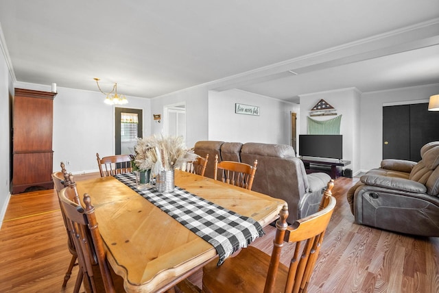 dining space featuring an inviting chandelier, crown molding, and light wood finished floors