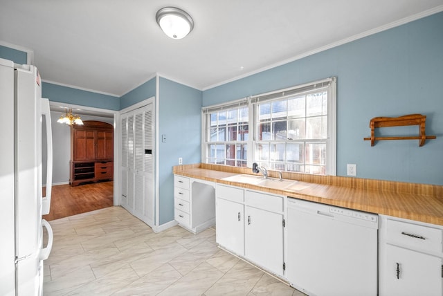 kitchen with white appliances, an inviting chandelier, ornamental molding, a sink, and white cabinets