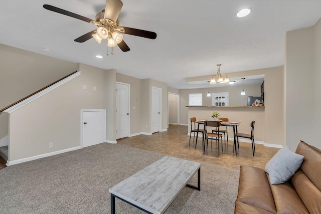 carpeted living area with recessed lighting, stairway, baseboards, and ceiling fan with notable chandelier