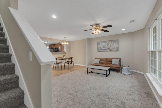 living area featuring recessed lighting, baseboards, stairs, and ceiling fan with notable chandelier