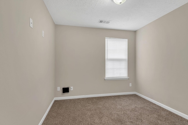 spare room featuring visible vents, carpet floors, a textured ceiling, and baseboards