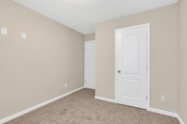 unfurnished bedroom with a textured ceiling, baseboards, and carpet floors