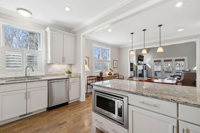 kitchen featuring visible vents, a sink, light wood-style floors, appliances with stainless steel finishes, and crown molding