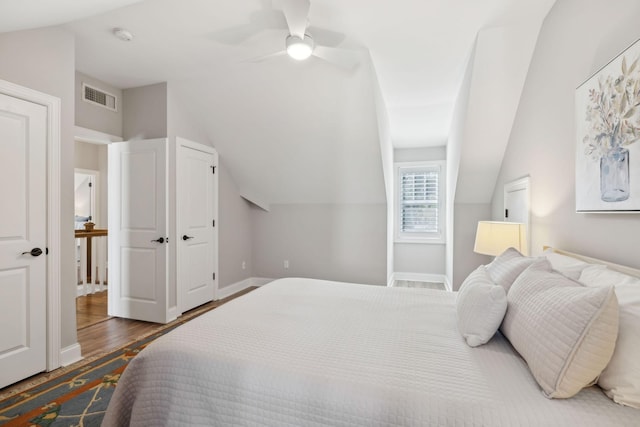 bedroom featuring visible vents, baseboards, wood finished floors, and vaulted ceiling