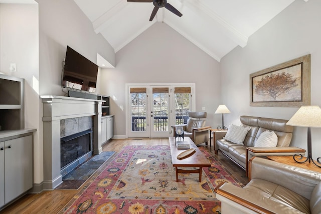 living room with wood finished floors, baseboards, high vaulted ceiling, a high end fireplace, and ceiling fan