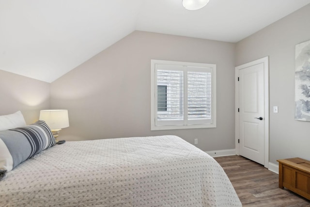 bedroom with baseboards, wood finished floors, and vaulted ceiling