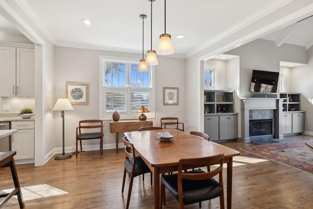 dining room featuring a premium fireplace, baseboards, light wood-style floors, and ornamental molding