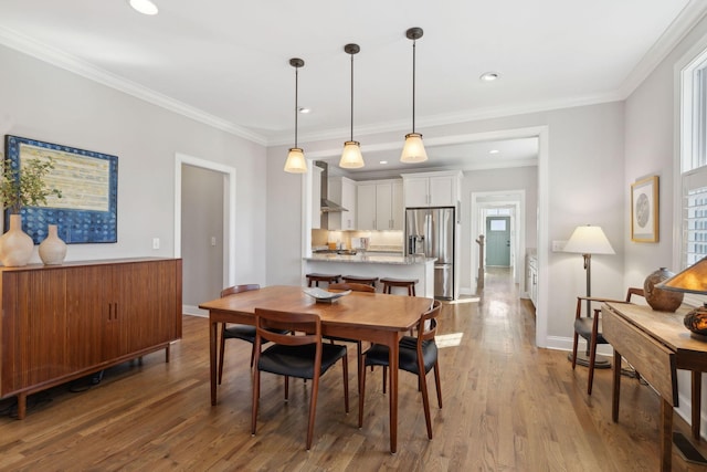 dining area featuring wood finished floors, baseboards, and ornamental molding