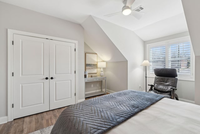 bedroom featuring visible vents, baseboards, vaulted ceiling, wood finished floors, and a closet