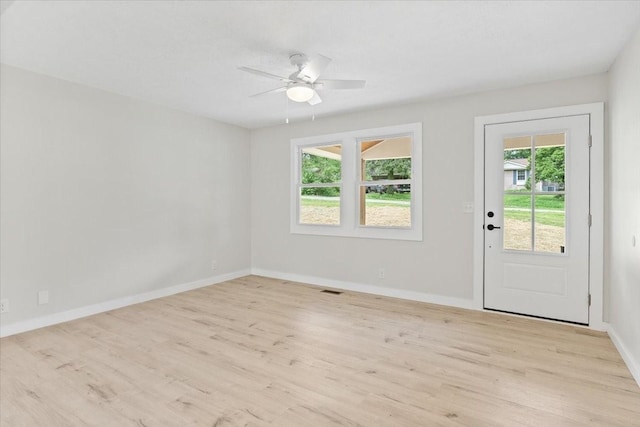 foyer entrance with visible vents, light wood-style flooring, a ceiling fan, and baseboards