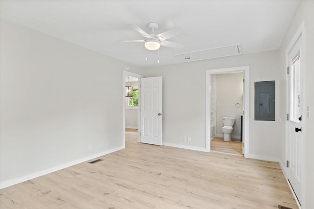 unfurnished bedroom with visible vents, light wood-style flooring, electric panel, baseboards, and attic access