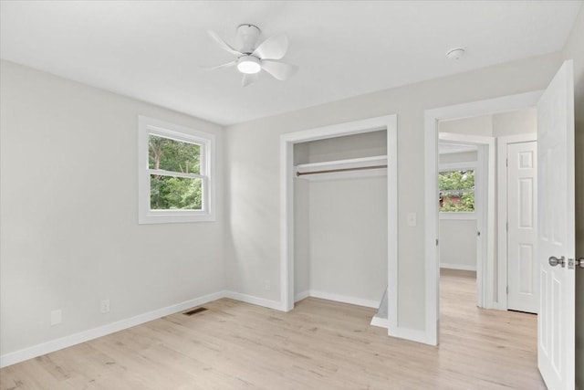 unfurnished bedroom featuring visible vents, multiple windows, and light wood-style floors