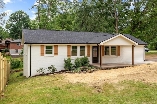 ranch-style house with a front lawn, a patio, fence, roof with shingles, and brick siding