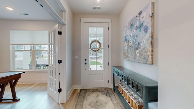 entryway with light wood finished floors, visible vents, and baseboards