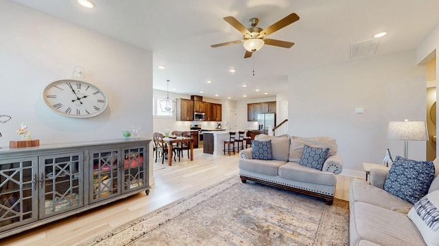 living area with baseboards, visible vents, light wood finished floors, recessed lighting, and ceiling fan