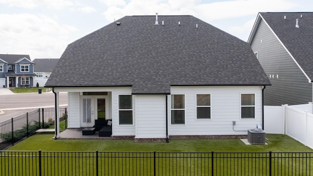 back of property with a fenced backyard, a yard, and roof with shingles