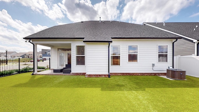 rear view of property with cooling unit, a lawn, roof with shingles, and fence