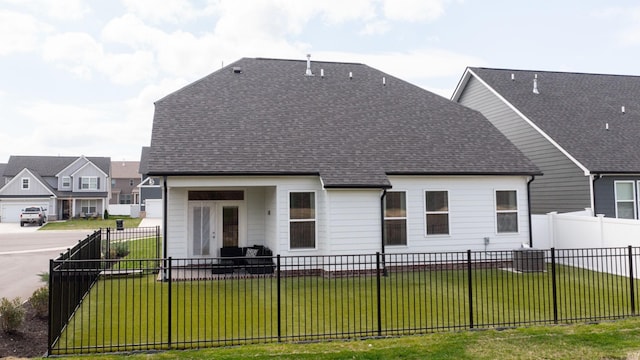 back of house featuring a yard, a fenced backyard, and roof with shingles