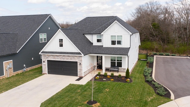 view of front facade featuring stone siding, board and batten siding, roof with shingles, concrete driveway, and a front yard