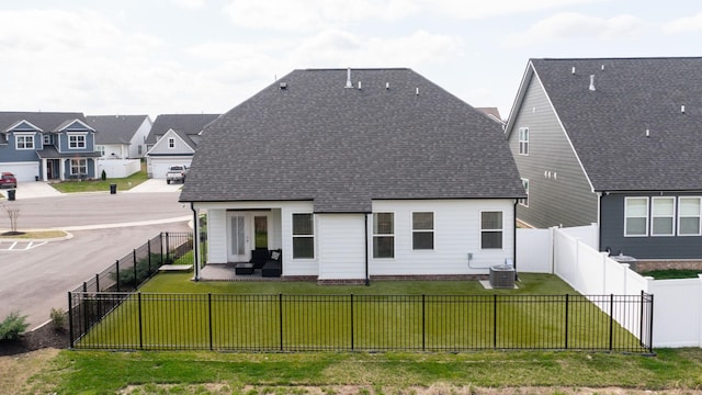 back of house with a shingled roof, central air condition unit, a fenced backyard, a yard, and a patio area