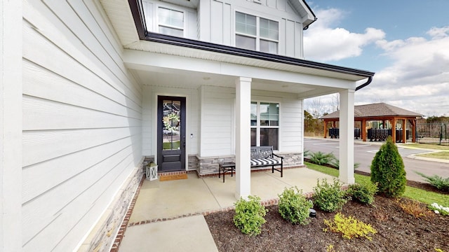 view of exterior entry featuring stone siding, a porch, and board and batten siding