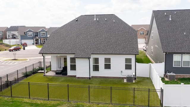 back of house with central AC unit, a lawn, roof with shingles, and a fenced backyard