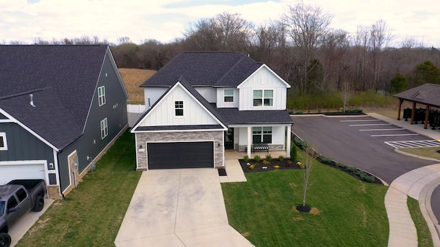 view of front of property featuring board and batten siding, a front yard, roof with shingles, stone siding, and driveway