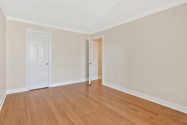 spare room with light wood finished floors, baseboards, and ornamental molding