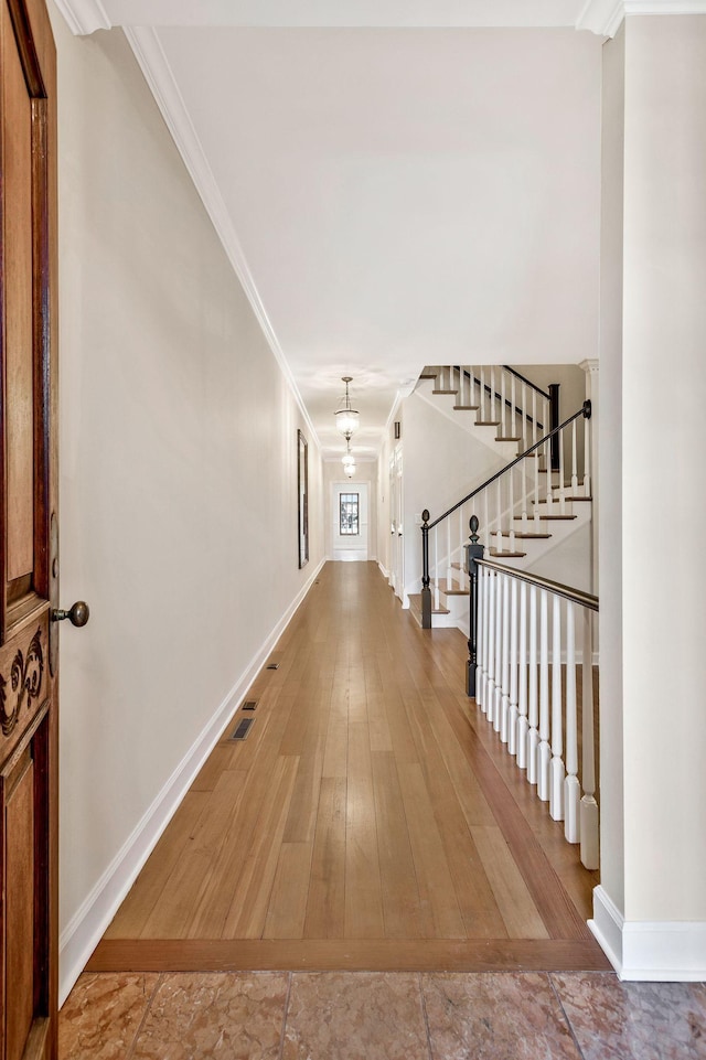 corridor featuring visible vents, crown molding, baseboards, stairs, and wood-type flooring