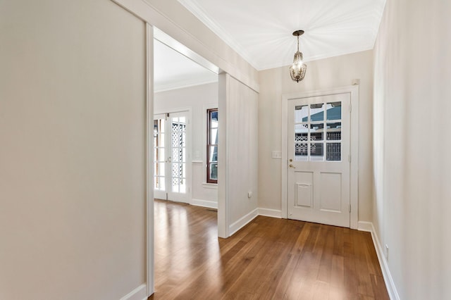 entryway featuring a notable chandelier, ornamental molding, baseboards, and wood-type flooring