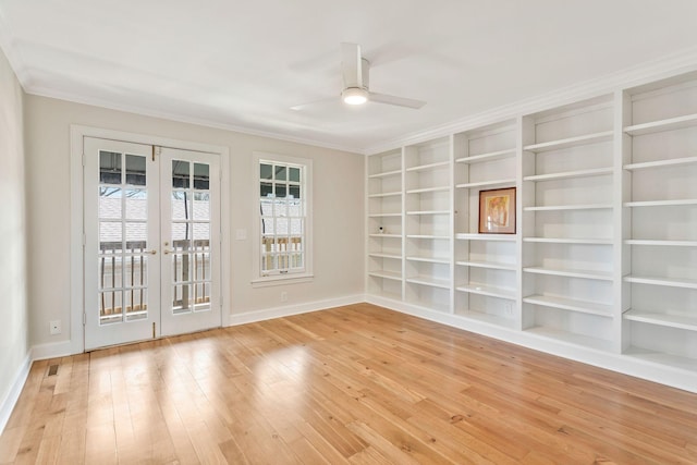 empty room featuring built in shelves, ornamental molding, hardwood / wood-style floors, french doors, and a ceiling fan