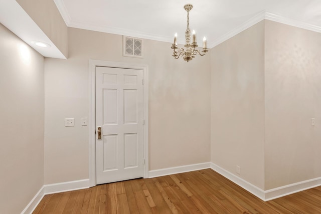 spare room with visible vents, baseboards, ornamental molding, light wood-style floors, and a notable chandelier