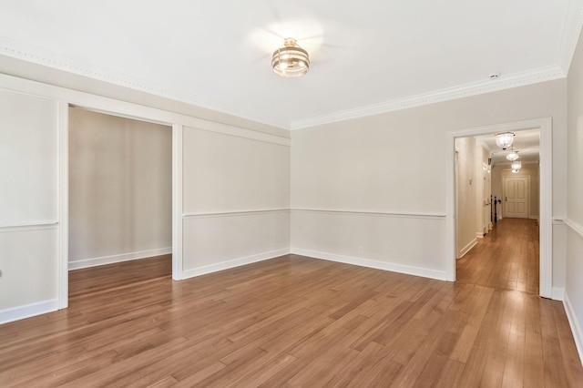 empty room with baseboards, light wood-style floors, and crown molding