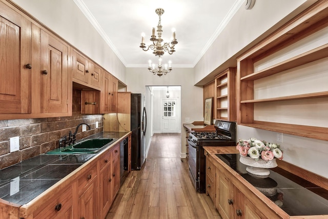 kitchen with a sink, black appliances, crown molding, light wood-type flooring, and a chandelier