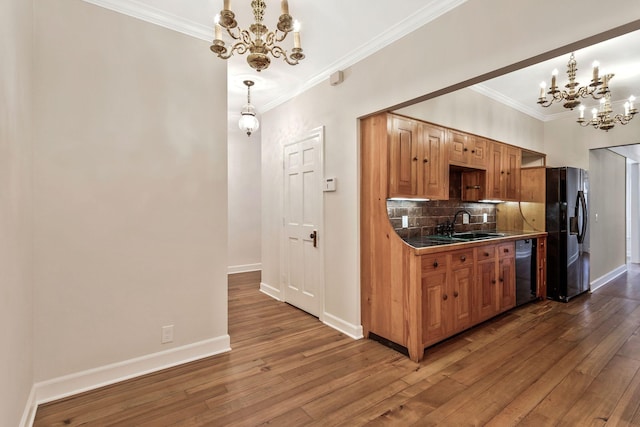 kitchen with black appliances, ornamental molding, tasteful backsplash, wood-type flooring, and an inviting chandelier