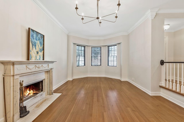 unfurnished living room with hardwood / wood-style floors, baseboards, a chandelier, and ornamental molding