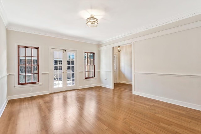 unfurnished room featuring plenty of natural light, ornamental molding, french doors, and wood finished floors